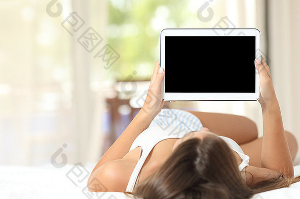 女孩躺在家里的床上，使用并显示一个空白的平板电脑屏幕