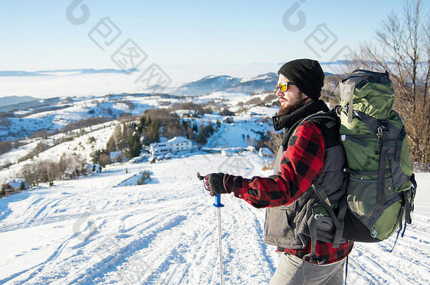 站在雪山上的留着胡子的背包客