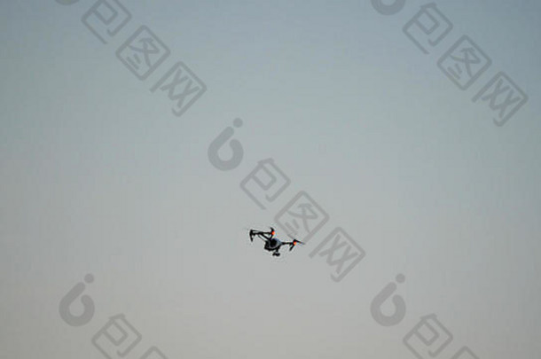 带摄像头的黑色无人机四架直升机飞越蓝天。天空中黑色的嗡嗡声。在空中飞行的四翼无人机，装有数码相机，用于视频和<strong>照片制作</strong>