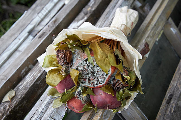 一束腐烂的水果和<strong>枯萎</strong>的花朵躺在一座破木屋的废墟上。