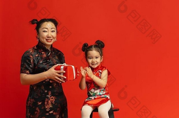 送礼物和幸福。2020年中国新年快乐。传统服装红色背景上的亚洲母女肖像。庆祝，人类情感，节日。空间。
