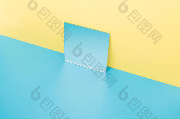 在黄色背景上隔离的蓝色桌子上的镜子图片