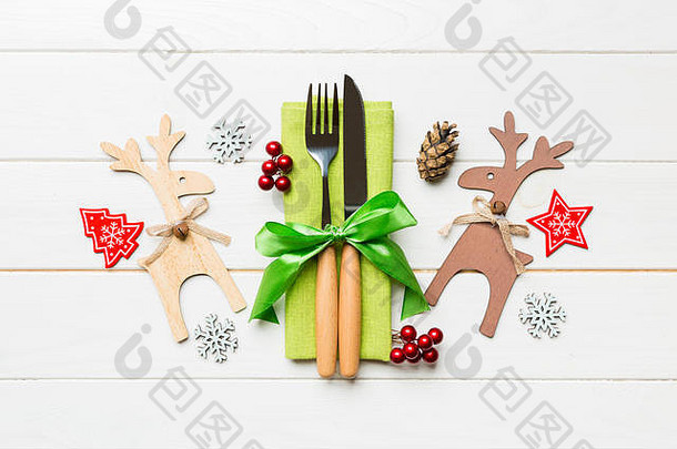 餐巾纸上<strong>新年</strong>用具的俯视图，带有节日装饰和木制背景上的驯鹿。圣诞晚餐概念的特写镜头。
