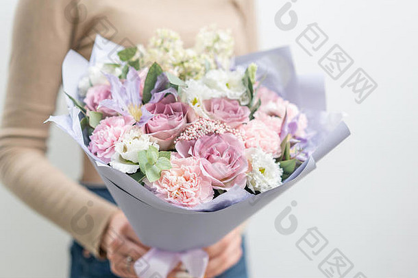 女人手里拿着一束美丽的鲜花。花店花匠的工作。精致柔和的颜色。鲜切花。粉红和丁香