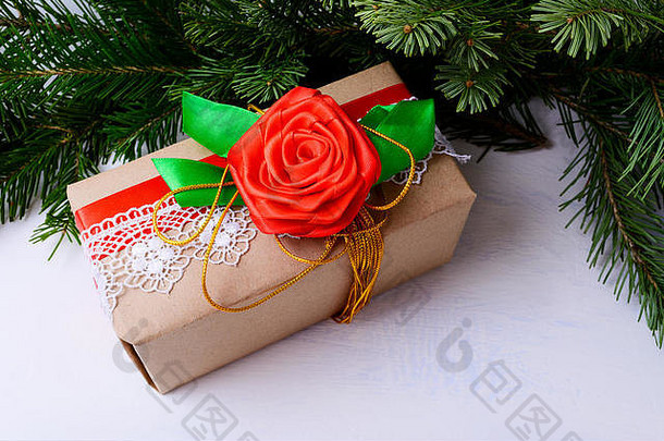 用花边和红色丝质玫瑰装饰的圣诞礼品盒。圣诞背景与杉木枝和牛皮纸包装礼物。