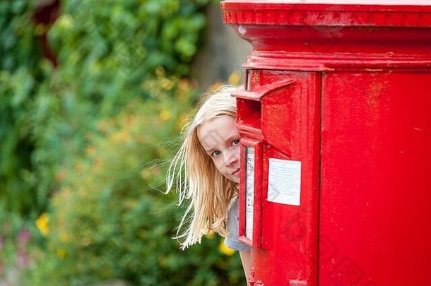 年轻的金发女郎女孩开业后传统的红色的英国帖子盒子