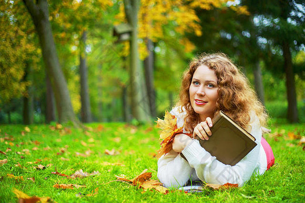美丽的年轻的plussize女人<strong>阅读</strong>书秋天公园