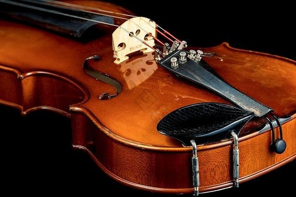 在黑色背景下拍摄的一张老小提琴的工作室照片。