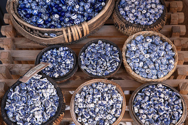 市场上出售的装满蓝色和白色珠子的编织篮子