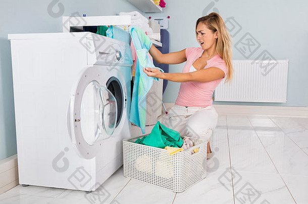 在<strong>杂物间</strong>的洗衣机里洗完衣服后看衣服的年轻女子