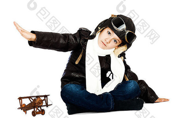 快乐可爱的男孩，穿着像二战飞行员一样，在白色背景下玩木制飞机玩具。复古风格