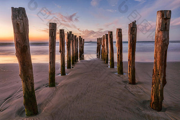 新西兰奥塔哥达尼丁圣克莱尔海滩日出时的旧码头立柱。