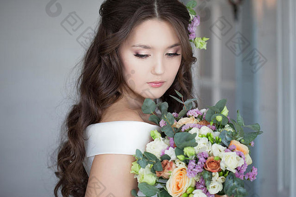 穿着白色连衣裙的美丽优雅的新娘。一位迷人的年轻女子即将结婚。一位带花束的时尚新娘的肖像。