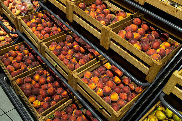 超市柜台上带柔软圆润桃子的木制接线盒的对角线视图