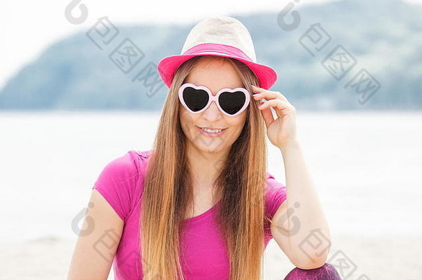 海滩上戴着草帽、戴着心形太阳镜的快乐女孩游客，在海边休息<strong>消夏</strong>