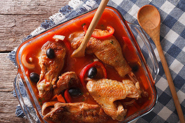 在玻璃碗里用番茄酱、橄榄和胡椒炖成的鸡块特写镜头。垂直俯视图
