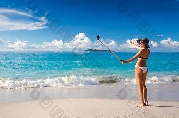 一个美丽的女人在海滩上给自己拍照