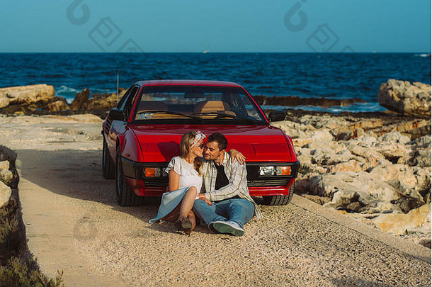 年轻的夫妇坐着前面红色的车海边马耳他
