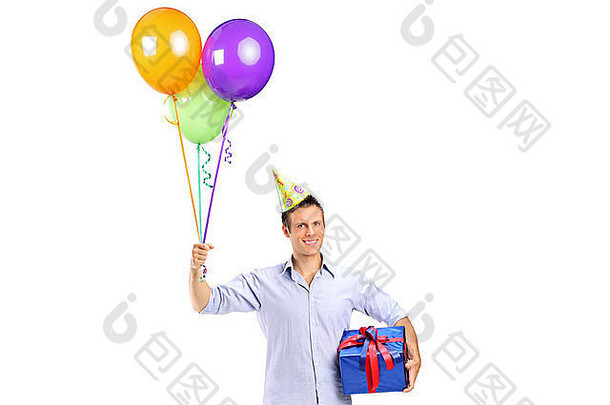 一个面带微笑的年轻人拿着礼物，气球孤立在白色的地板上