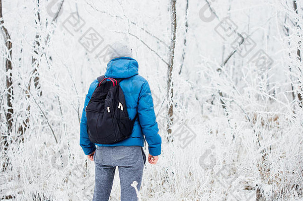 年轻人独自站在冬天的雪林中