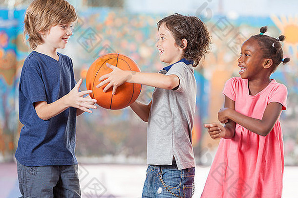 快乐的多民族孩子在学校打篮球。