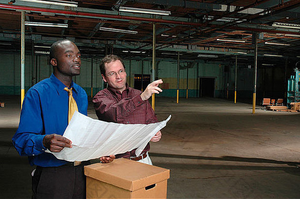两个男人在一个空荡荡的工厂或仓库里规划他们的创业未来