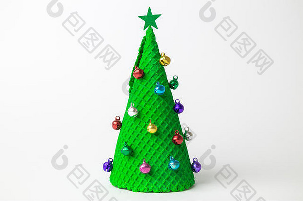圣诞树形状的绿色冰淇淋蛋筒，白色背景上装饰着五颜六色的小装饰品和星星，这是一个极简创意的节日和食物概念。