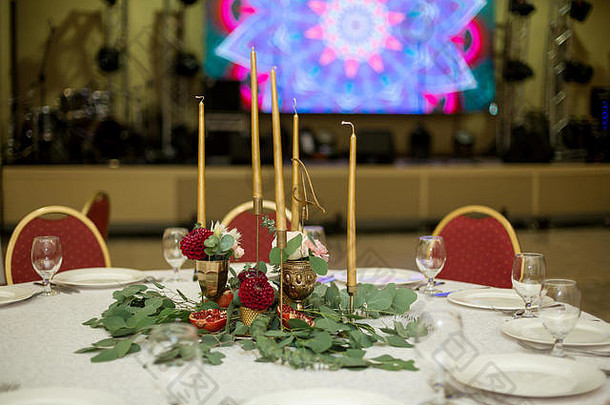 餐厅内装饰华丽的圆形宴会桌。鲜花是金色的蜡烛和红色的椅子。非常富有。
