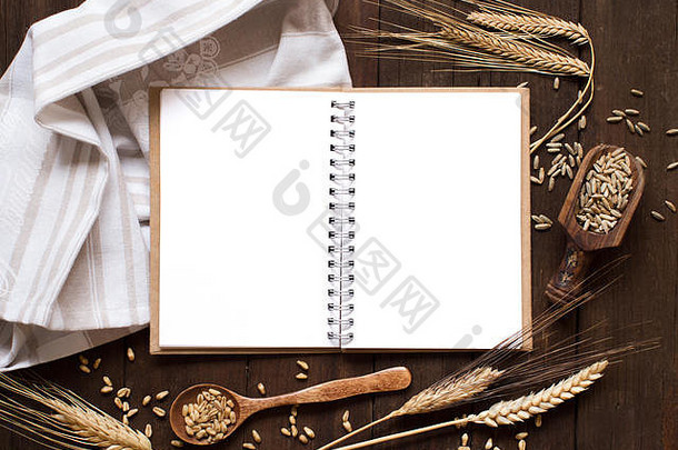笔记本和麦子放在有旧木头背景的餐巾上