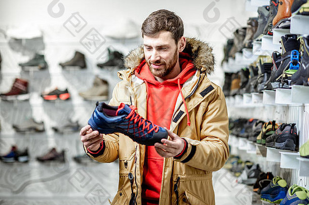 穿冬衣的男人在运动商店里选择<strong>登山鞋</strong>