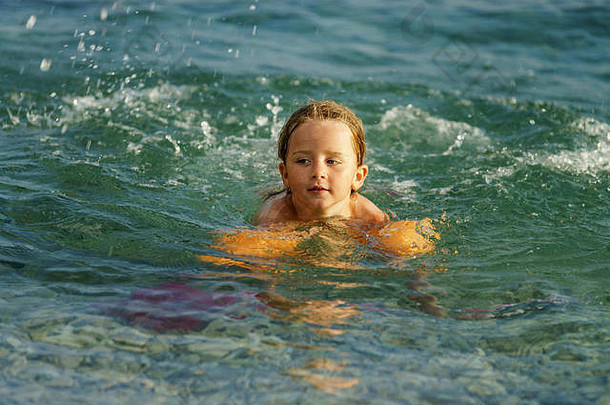 可爱的小女孩带着水翅膀在海里游泳，童年的概念