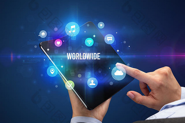商人手持可折叠智能手机，上面写着世界各地的文字、社交媒体概念