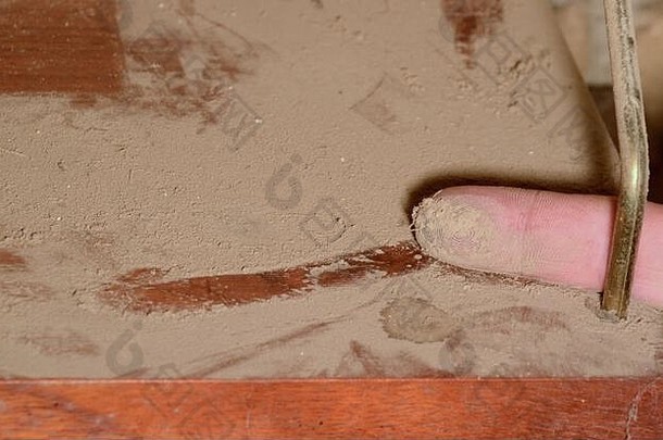 架子上的灰尘，一个手指在灰尘中画了一条线，并显示了捕获物