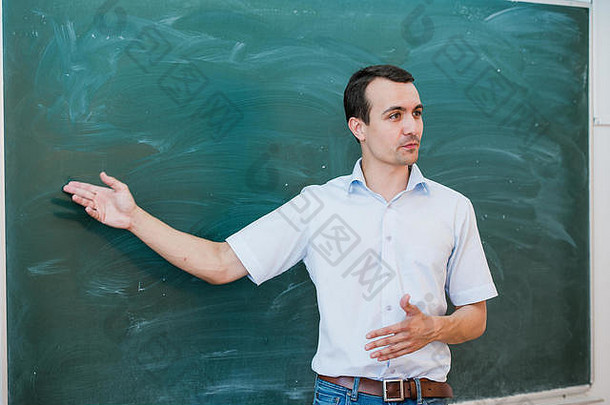 肖像年轻的英俊的学生老师类指出空白黑板会说话的微笑