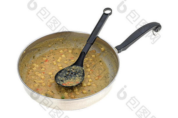 一个平底<strong>锅</strong>，上面有剩汤和一把黑汤匙，背景为白色。