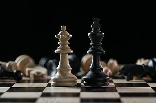 棋子皇后和国王在一队倒下的棋子面前，经过一场黑幕背景下的棋盘战场，滥用职权