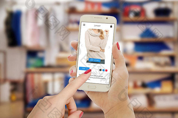 在电子商务网站或应用程序上使用智能<strong>手机</strong>进行在线购物。服装店在后台。