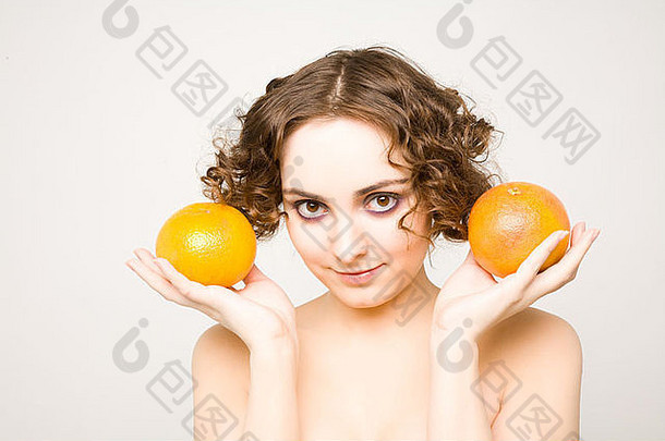 美丽的卷曲的女孩持有葡萄柚