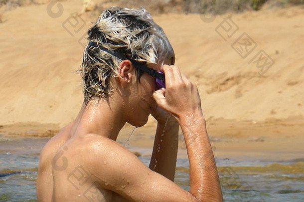 金发男孩戴着浮潜眼镜在海里洗澡
