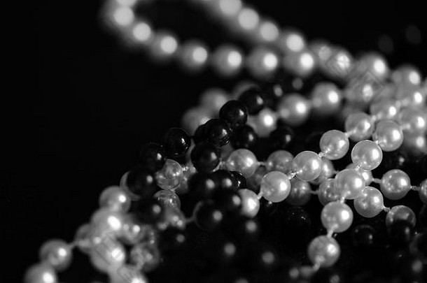黑色和白色串珠项链，背景为深色，特写。非黑即白的