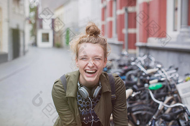 在城市街道上描绘一位戴着耳机的热情、欢笑的年轻女子