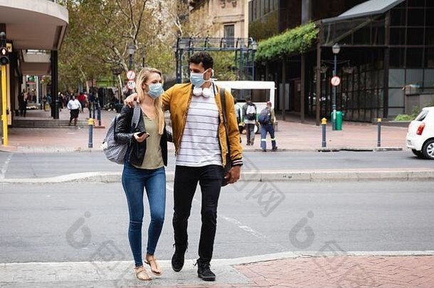 一对高加索夫妇戴着冠状病毒19型口罩在城里散步