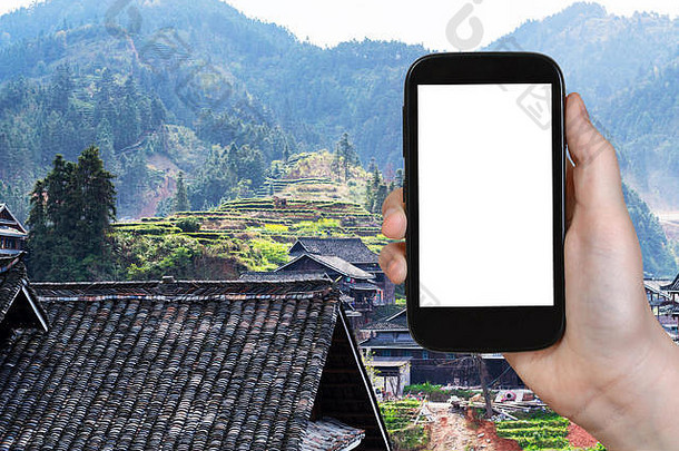 旅游理念——游客在春天用智能手机拍摄中国三江侗族自治县城阳村的乡村房屋