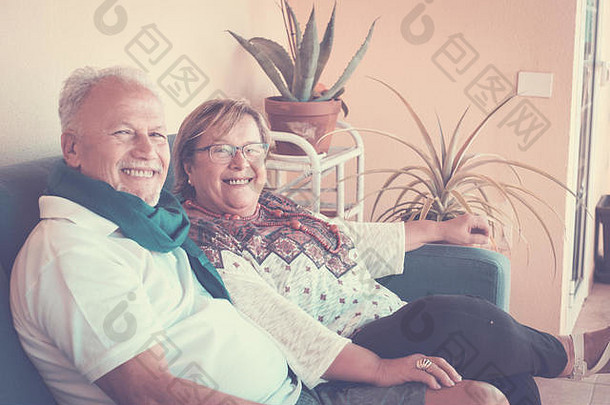 一对年老的祖父夫妇坐在地上的沙发上。闲暇是一段充满乐趣和微笑的美好时光。复古明亮过滤器。