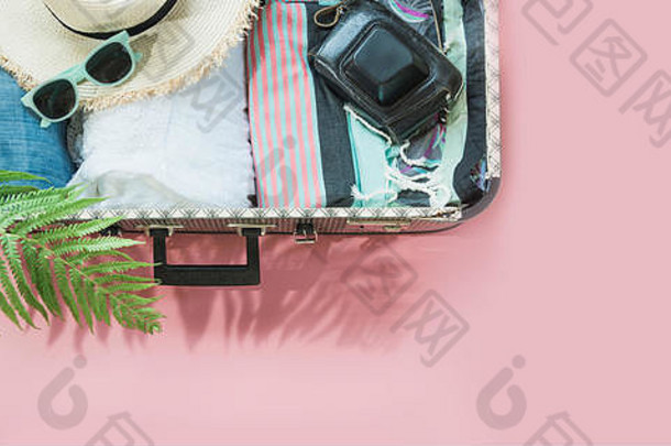 打开手提箱，穿上粉色的女装，准备旅行。具有空间的俯视图。夏季概念旅游。