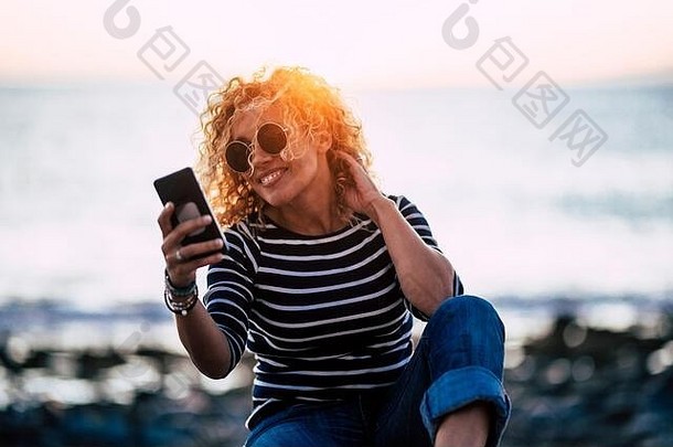 快乐的有吸引力的成人年轻的高加索人女人移动现代移动电话户外日落背景人技术户外法律