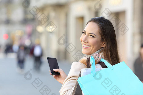 快乐购物者持有聪明的电话空白购物袋走街