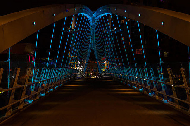 千禧年大桥的图片，它连接着萨尔福德码头和特拉福德公园，横跨曼彻斯特运河。拍摄于深夜。