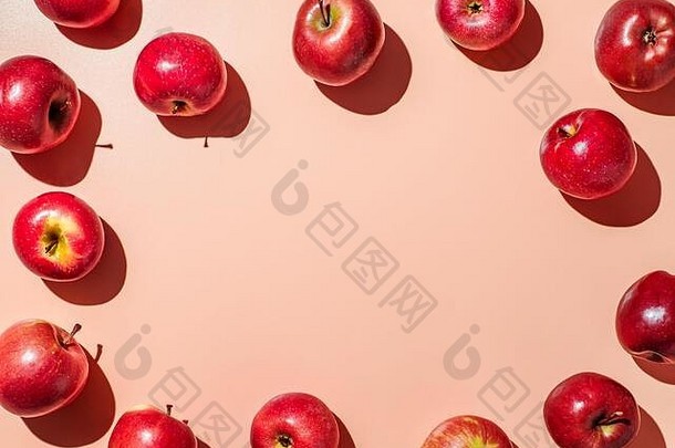 橙色或珊瑚粉色背景上的红苹果，中间有文本或设计的空间。五颜六色的水果架。创意概念。平放或俯视图，强光