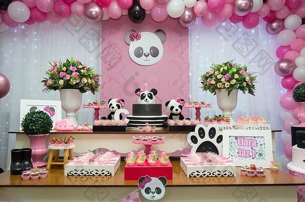 一桌糖果和生日蛋糕。以熊猫为主题的女孩派对——精致的粉色和白色装饰。一岁生日派对。